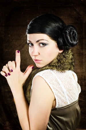 Retro portrait of brunette woman making a gun with hands