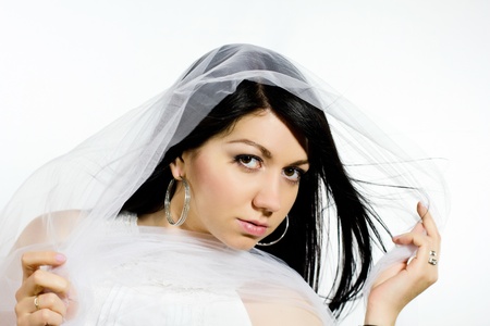 Young brunette posing while holding her white veil into the windの写真素材