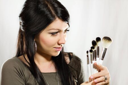 Beautiful woman holding makeup brushes set and looking on itの写真素材