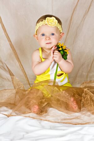 Pretty baby girl taking in her s arms the yellow flowerの写真素材