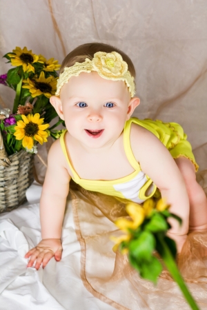 Baby is looking interested and try to reach the flowerの写真素材