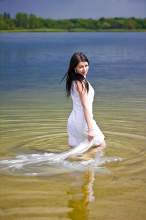 A beautiful brunette posing at a calm lakeの写真素材