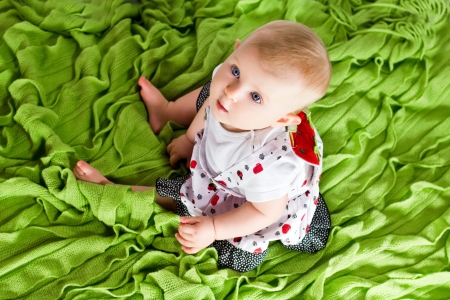 Baby sitting on green plaid and looking up. Bird's-eye viewの写真素材