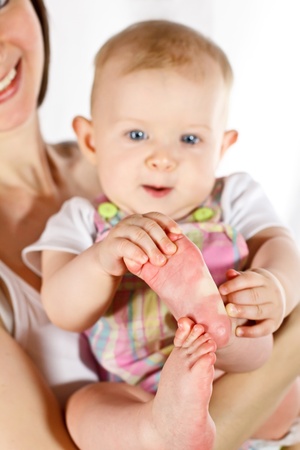 Baby catching its feet on mother's hands; focused on feetの写真素材