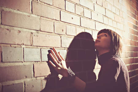 Woman at the brickwall looking upの写真素材