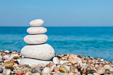 Zen stones stacked at beach against a blue sky and sea with copy spaceの写真素材