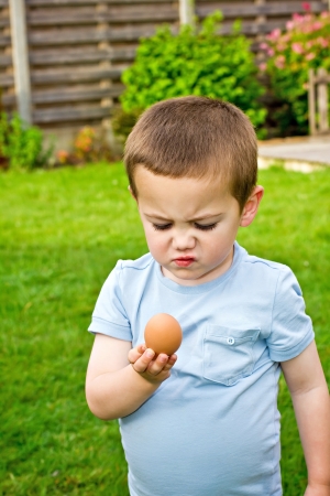 A boy holding and surprised looking on the raw fresh eggの写真素材