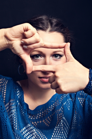 Beautiful woman showing framing hand gesture, black backgroundの写真素材