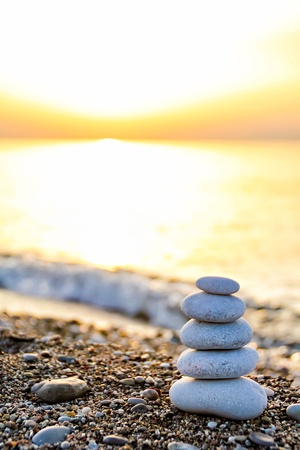 Zen-like stone pyramid on the beach at the sunriseの写真素材