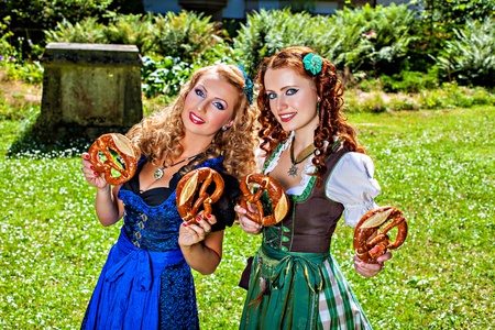 Two girls in dirndl dress holding pretzelの写真素材
