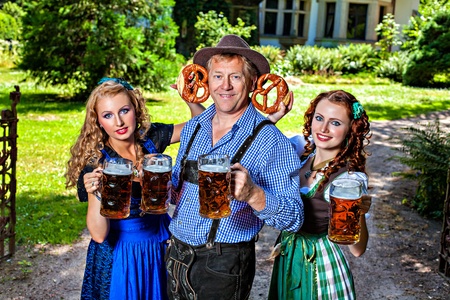 Group of men and women in traditional german Tracht with beer and pretzelの写真素材