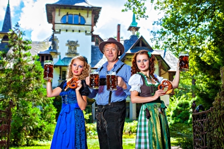 Group of men and women in traditional german Tracht with beer and pretzelの写真素材