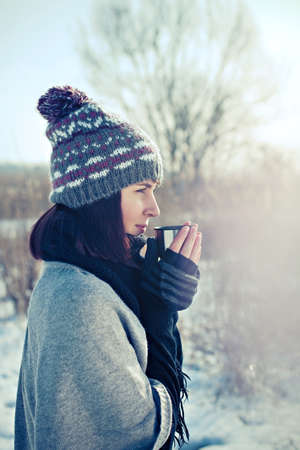 Portrait of the beautiful girl drinking hot tea in snowy winterの写真素材