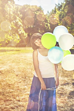 Young beautiful girl holding colorful balloons outdoorsの写真素材