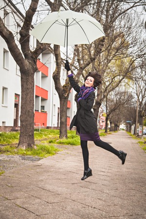 Happy young woman flying with umbrellaの写真素材
