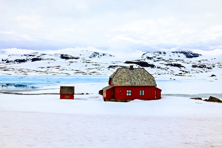 Red farm house on the background of mountainsの写真素材