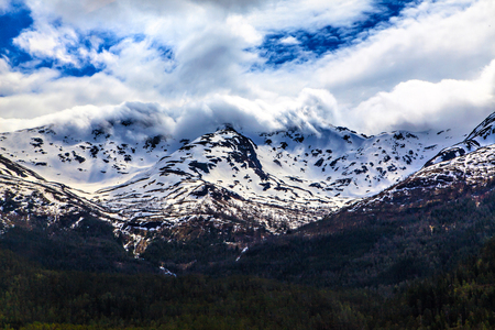 The norwegian landscape: snowy mountain in cloudsの写真素材