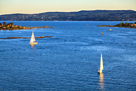 Sailboat sailing towards sunset on a calm eveningのeditorial素材