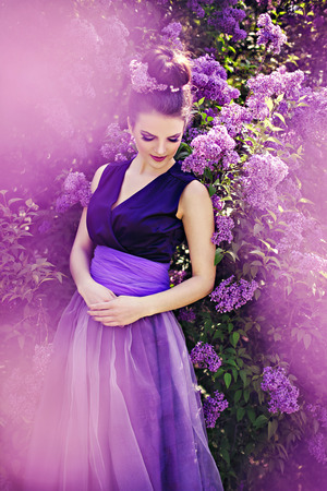 Beautiful girl in lilac ball dress among the flowers in the gardenの写真素材