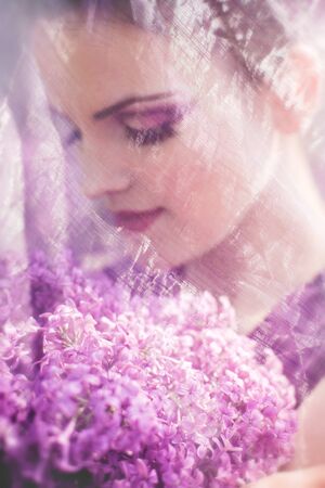 Beautiful girl in lilac ball dress among the flowers in the gardenの写真素材