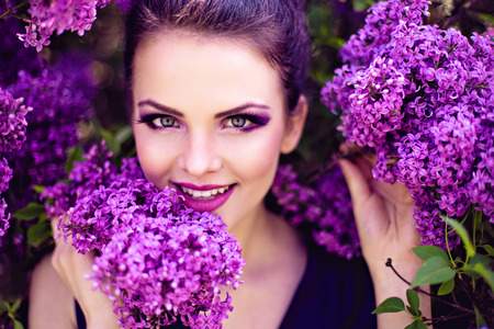 Beautiful girl in lilac ball dress among the flowers in the gardenの写真素材