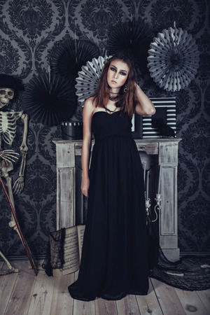 Mysterious young woman in black dress in dark roomの写真素材