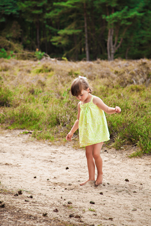 Little cute girl in a sundress in the forest on the roadの写真素材