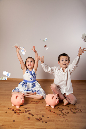 Happy little girl and boy throwing banknotesの写真素材