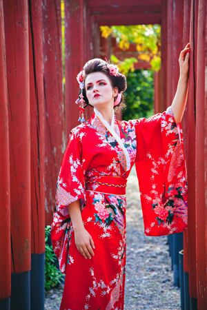 Young woman in geisha costume with fancy makeup in gardenの写真素材