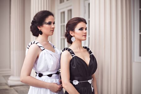 Vogue style photo of two ladies in black and white long dresses with fantasy make-upの写真素材