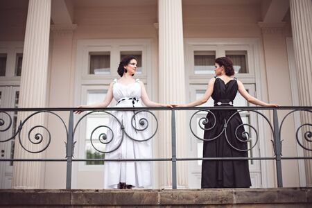 Vogue style photo of two ladies in black and white long dresses with fantasy make-upの写真素材