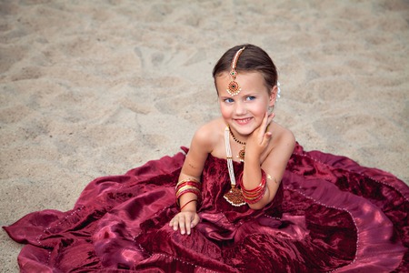 Happy little caucasian girl outdoors in traditional indian sari with oriental jewelleryの写真素材
