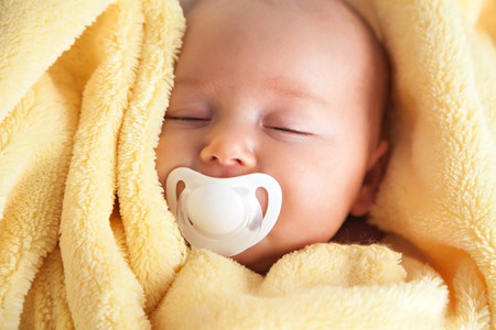 Frontal view of a cute baby girl with a soother in her mouth