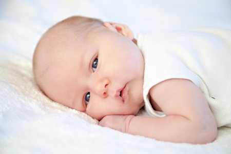 Portrait of a beautiful baby in white blanketの写真素材