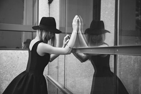 Portrait of young woman in black hat looking through the window