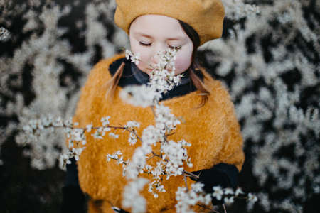 Little girl in early spring in park outdoor with flowering treesの写真素材