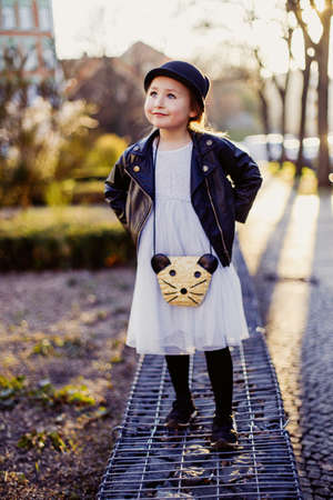 Little girl with a cat hat walking in the city in early spring in sunny weather, happy childhood and springtimeの写真素材