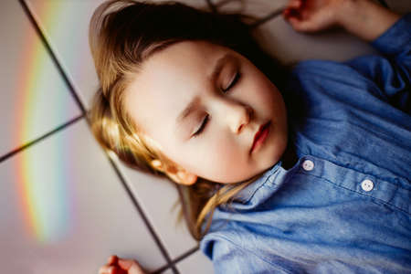 Rainbow reflection on face of little funny girlの写真素材