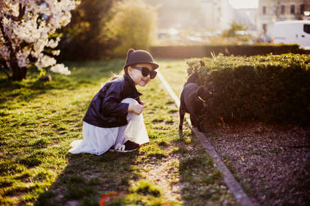 Cute little girl with black cat outdoors in spring at sunny weatherの写真素材