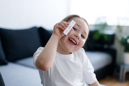 Kid girl with test strip for antibody or sars-cov-2 virus disease in handsの写真素材