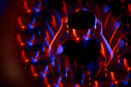Kid girl experiencing VR headset game on colorful background with effect reflections. Child using a gaming gadget for virtual reality. Futuristic goggles at young age. Virtual technology.の写真素材