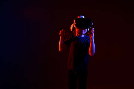 Girl 5 yo experiencing VR headset game on colorful background. Child using a gaming gadget for virtual reality. Futuristic goggles at young age. Virtual technology.の写真素材