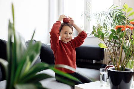 Healthy eating - child holding and eating an apple, lots of fresh fruit on the table in front at home, healthy lifestyle conceptの写真素材