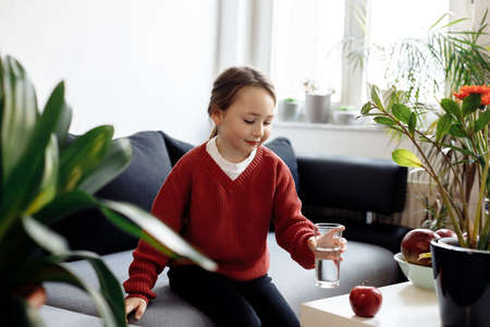 Healthy eating - child taking glass of water, lots of fresh fruit on the table in front at home, healthy lifestyle conceptの写真素材
