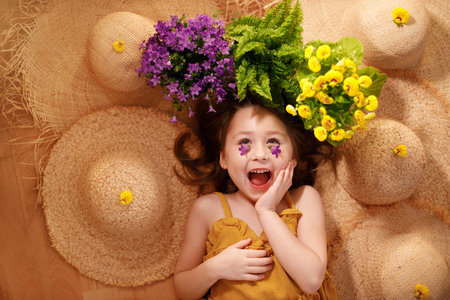 Portrait of a little girl lying on background with flowers and straw hat, summer and travel feeling concept.の写真素材