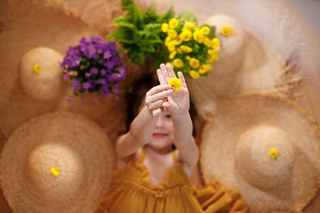 Close-up of hands of a little girl lying on background with flowers and straw hat, summer and travel feeling concept.の写真素材