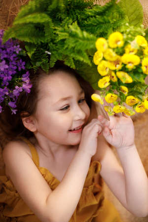 Portrait of a little girl lying on background with flowers and straw hat, summer and travel feeling concept.の写真素材