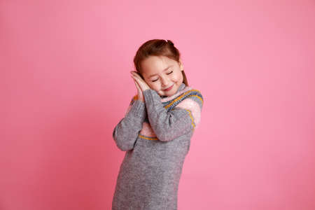 The little girl shows that wants to sleep, studio shoot on rosa background.の写真素材
