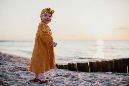 Little girl in oriental clothes walking along the beach at sunsetの写真素材
