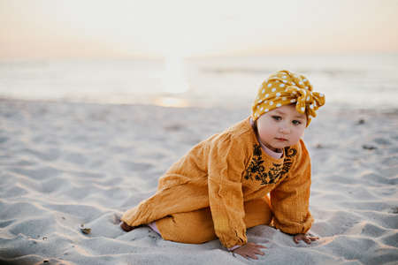 Little girl in oriental clothes walking along the beach at sunsetの写真素材